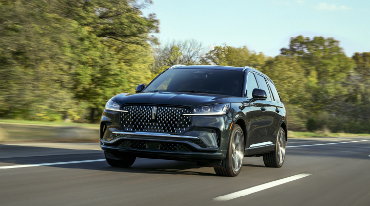 A 2025 Lincoln Black Label Aviator® SUV is being driven down a road lined with trees. | Irwin Lincoln Laconia in Laconia NH