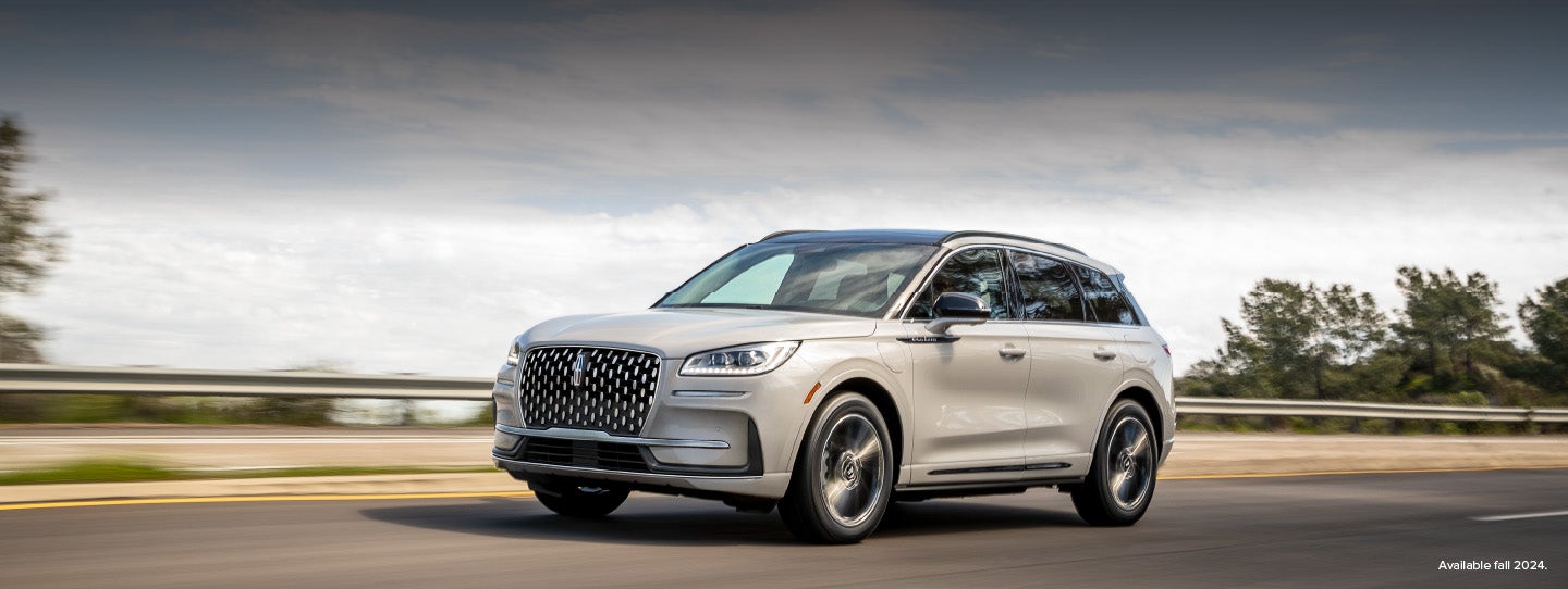A 2025 white Lincoln Corsair® Grand Touring Plug-in Hybrid SUV is being driven down a highway
