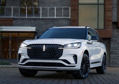 A 2026 Lincoln Aviator® Reserve model is shown with the available Jet Appearance Package parked near a restaurant. | Irwin Lincoln Laconia in Laconia NH