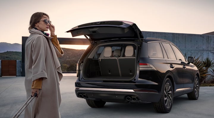 A woman approaches a 2026 Lincoln Aviator® SUV with its rear liftgate open. | Irwin Lincoln Laconia in Laconia NH