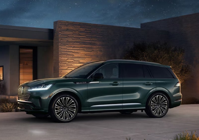 A green 2027 Lincoln Aviator® SUV is parked outside a contemporary home. | Irwin Lincoln Laconia in Laconia NH