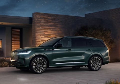 A green 2027 Lincoln Aviator® SUV is parked outside a contemporary home. | Irwin Lincoln Laconia in Laconia NH