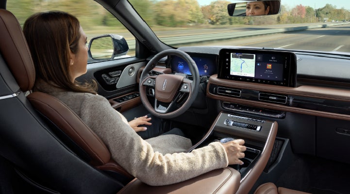 A 2027 Lincoln Aviator® SUV is being driven hands-free on a highway lined with trees. | Irwin Lincoln Laconia in Laconia NH