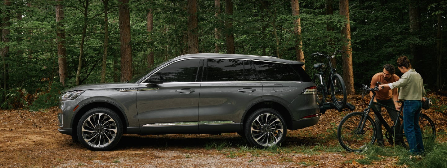 A father and son load e-bikes on a bike rack attached to a 2027 Lincoln Aviator® SUV. | Irwin Lincoln Laconia in Laconia NH